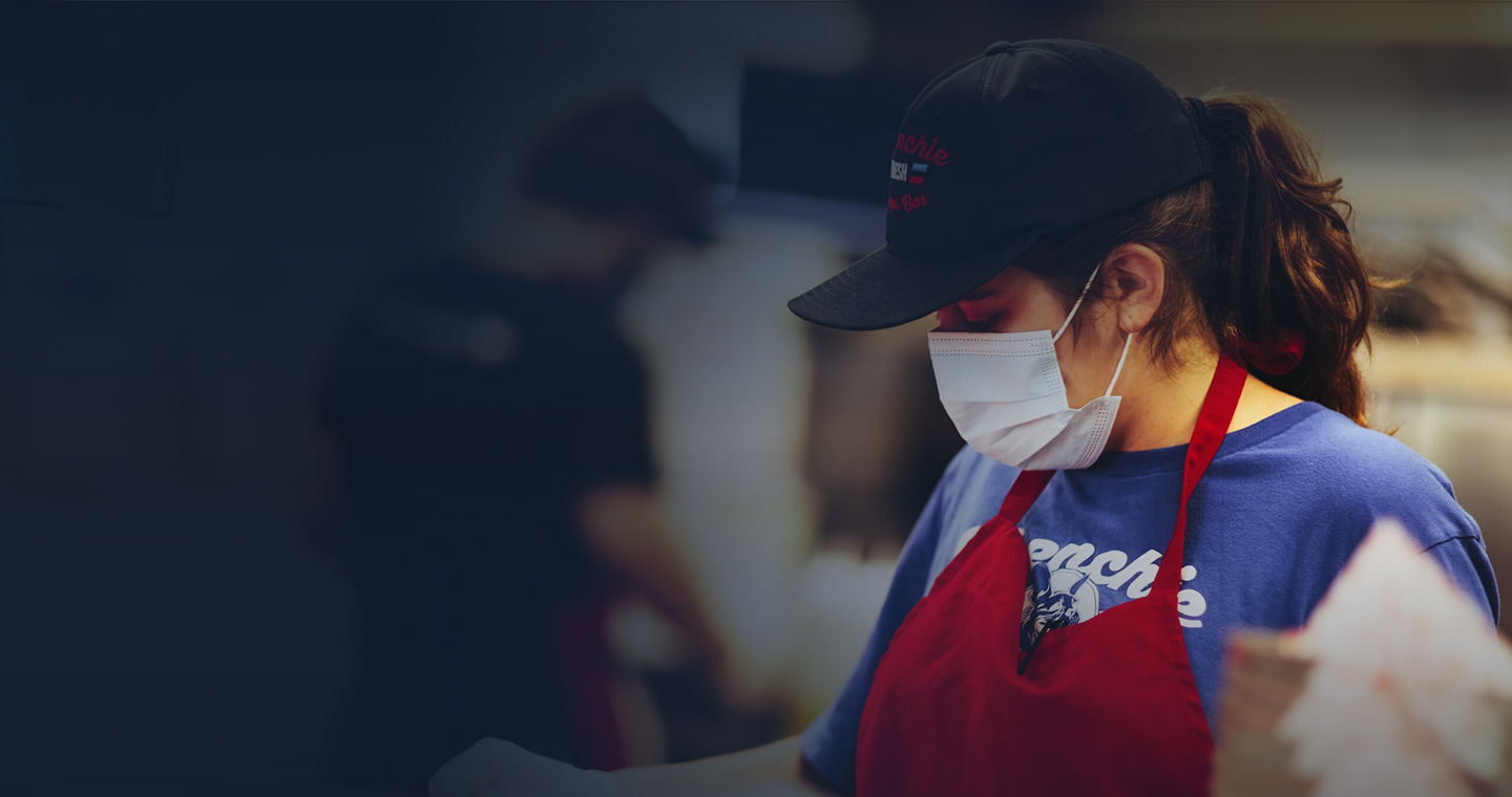 Cashier with covid mask, uniform and hat.