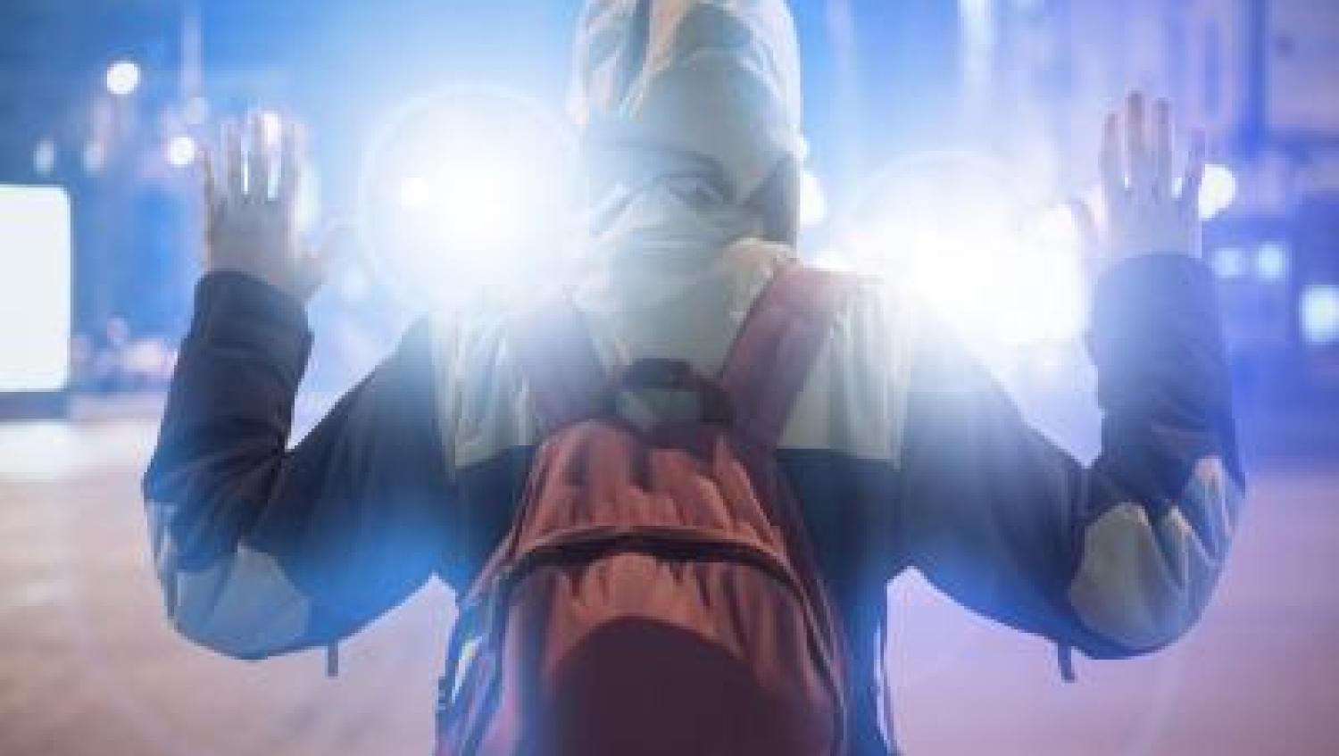 Person in hoody holding hands up, back facing view