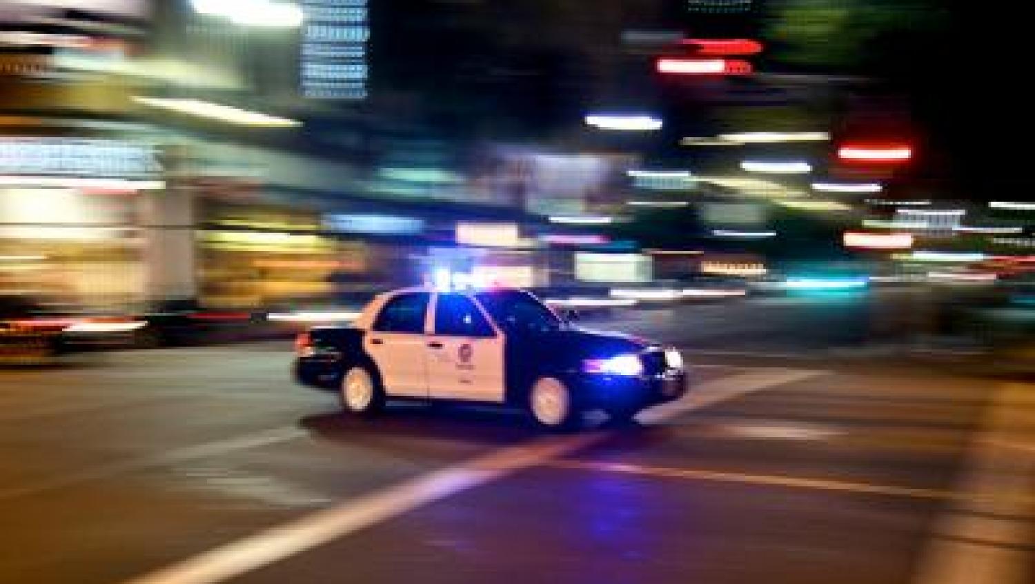 Police car responding to alarm, speeding through a city.