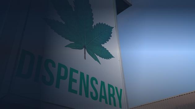 Large white dispensary sign with green cannabis leaf.