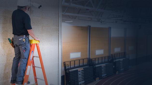 Construction worker installing alarm system into ceiling.
