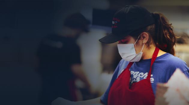 Cashier with covid mask, uniform and hat.