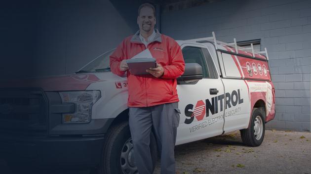 Sonitrol technician reviewing checklist in front of Sonitrol vehicle.