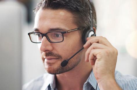 Call center phone operator with a headpiece and microphone and wearing glasses.