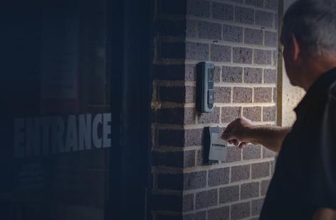 A man using his sonitrol badge to enter the building. 