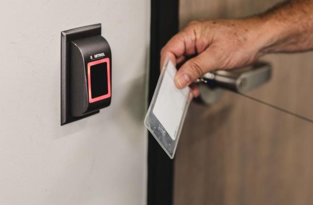 A hand moving a badge to open up a door. 