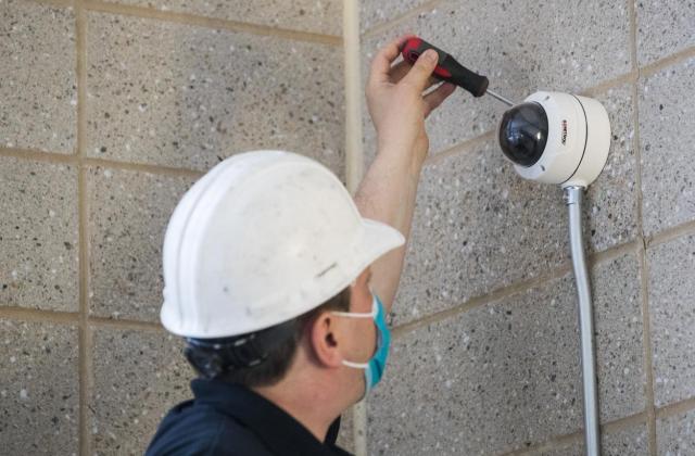 Sonitrol technician installing a camera onto a cement block wall.