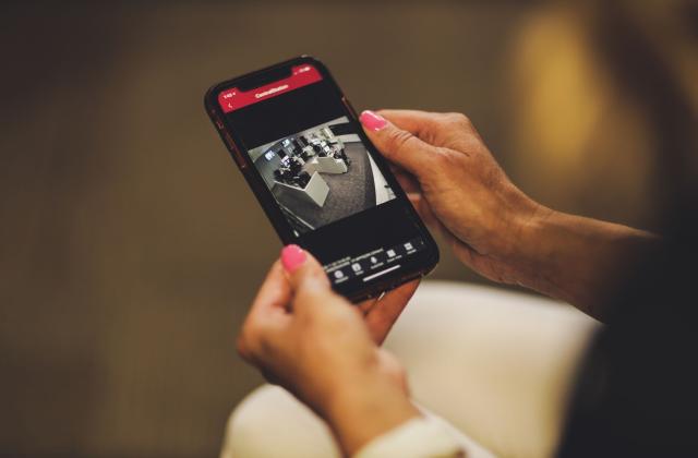 female holding phone with security camera screen showing